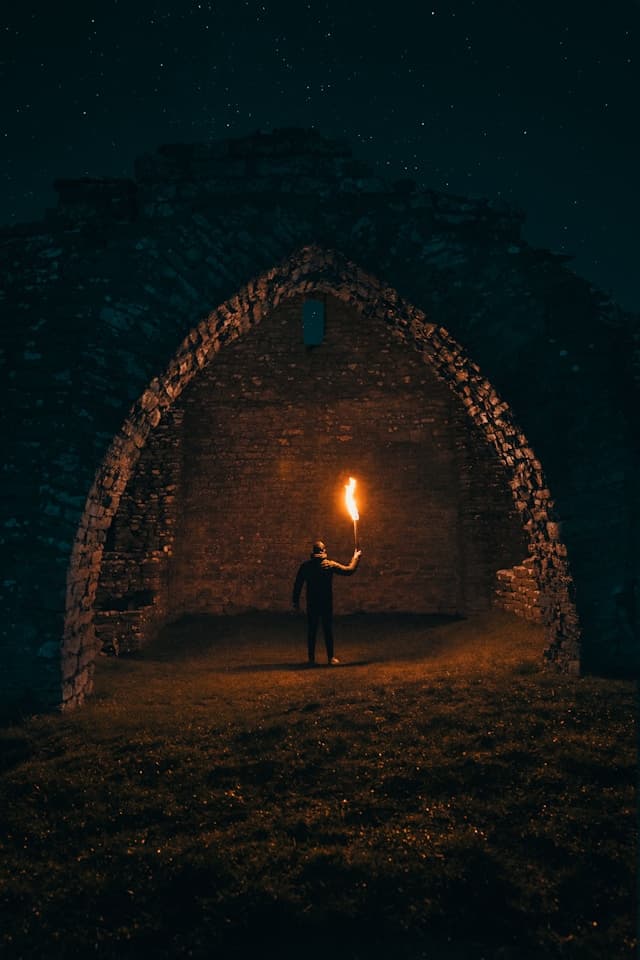 A photo of a lone adventurer exploring a cave with a torch.